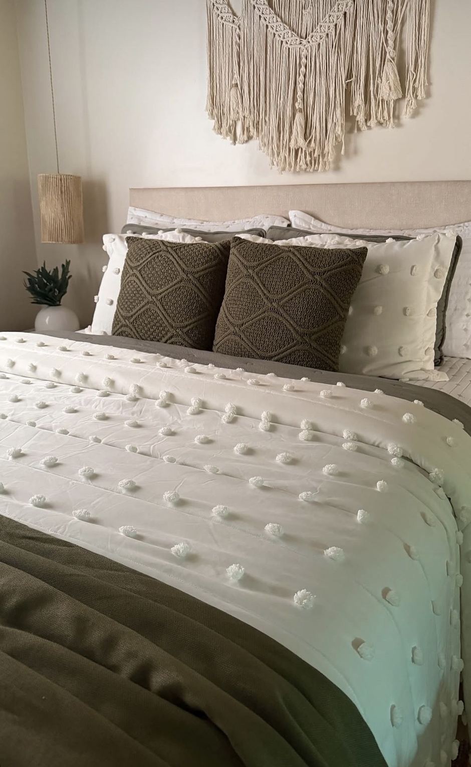 Cama arrumada com colcha branca e almofadas de tricô